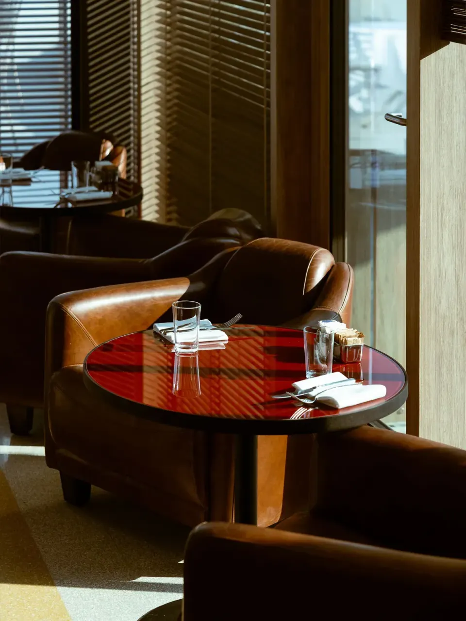 Leather armchairs around a small round table by a window in a bar at Hotel Calimala Milano